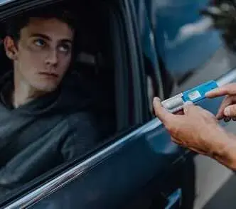 Officer handing a saliva drug test to a driver at a roadside check